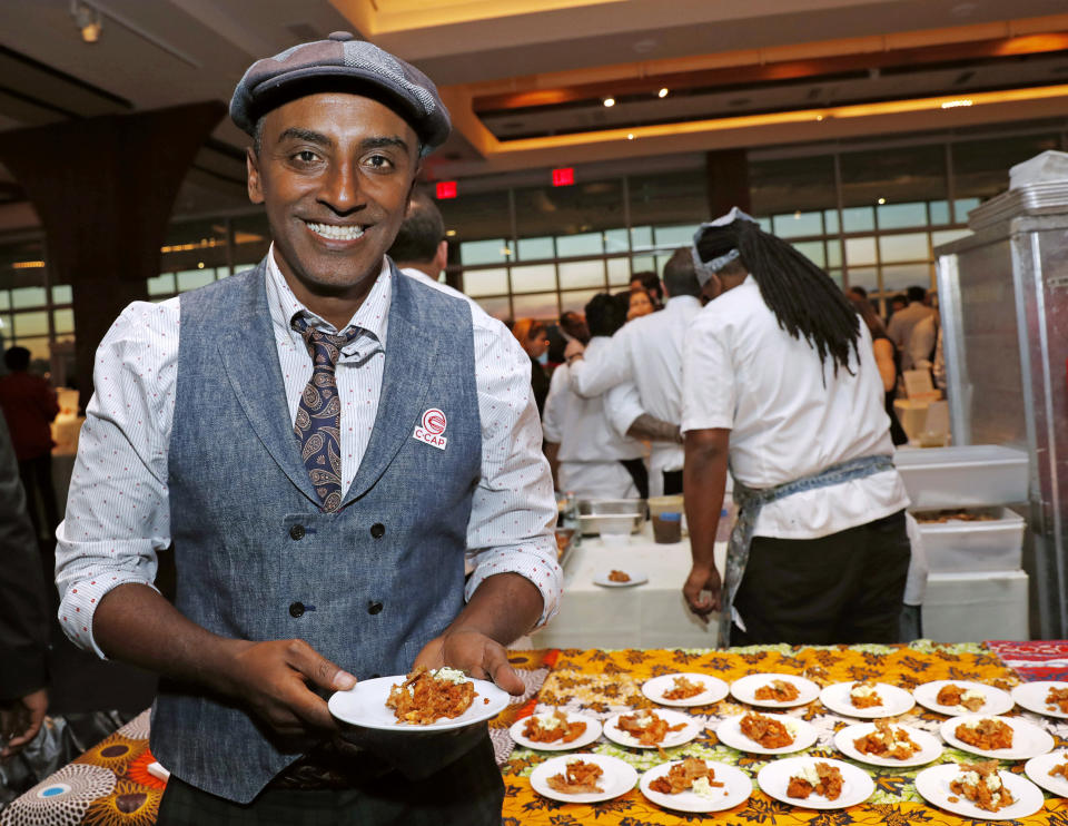 Chef Marcus Samuelsson, who is Ethiopian, but was raised in Sweden, founder of Red Rooster Harlem and more than a dozen other restaurants, holds a tasting plate of Dorowat "lasagna," with injera (Ethiopian flatbread), ayib (Ethiopian cheese), rosemary, and crispy skin, during the C-CAP (Careers through Culinary Arts Program) annual benefit, Tuesday, Feb. 27, 2018, in New York. (AP Photo/Kathy Willens)