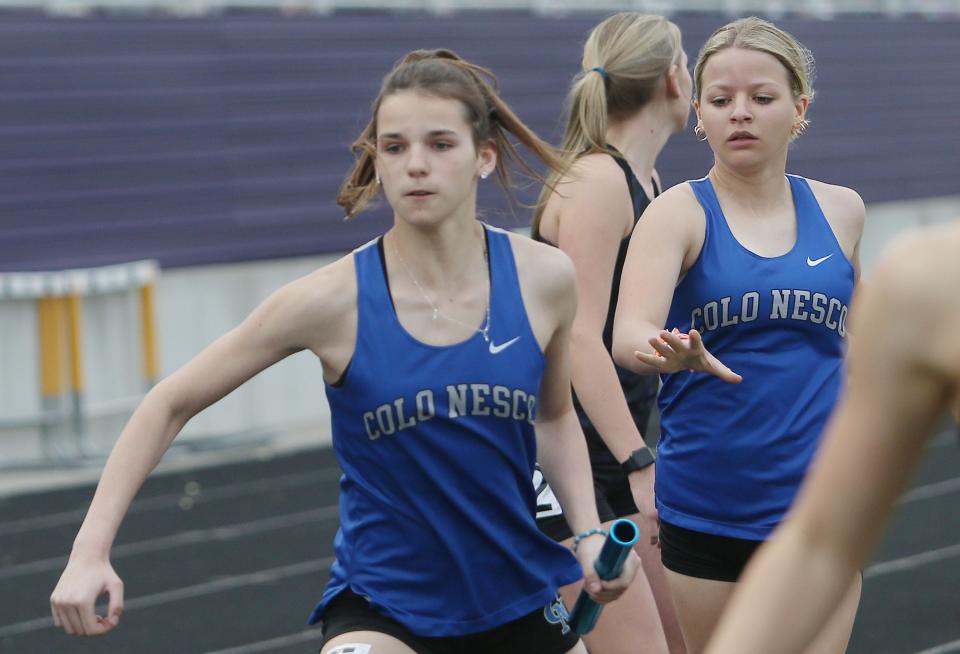 Colo-NESCO's Emma Lennie and Sophia Clawson exchange the baton during the girls' distance medley relay at the Dave Robinson Relays at Cub Stadium on April 14, 2023, in Nevada, Iowa. Colo-NESCO won the race in 2:03.00.