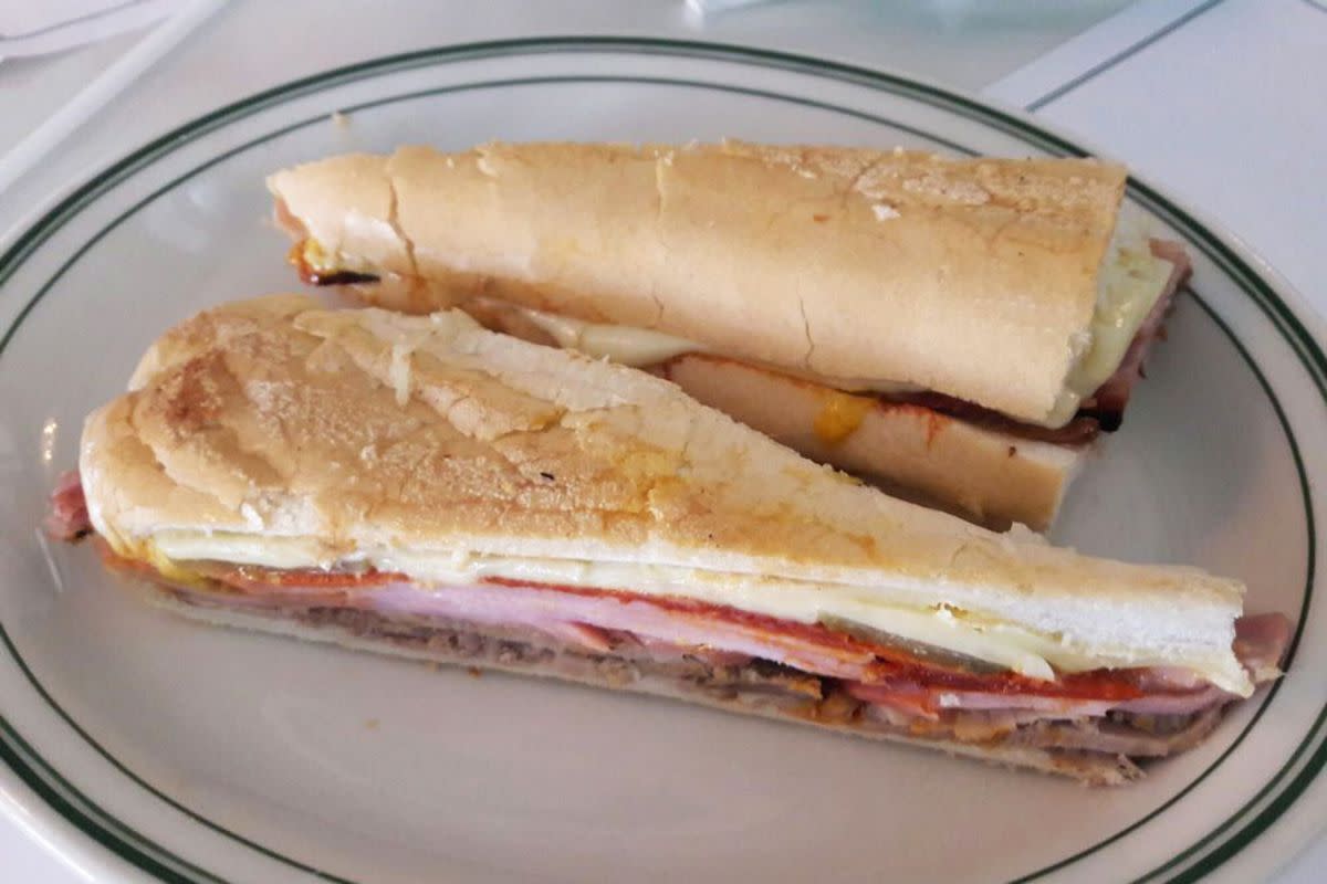 Cubano Sandwich on a black rimmed white ceramic plate, Versailles, Miami, on a white tablecloth