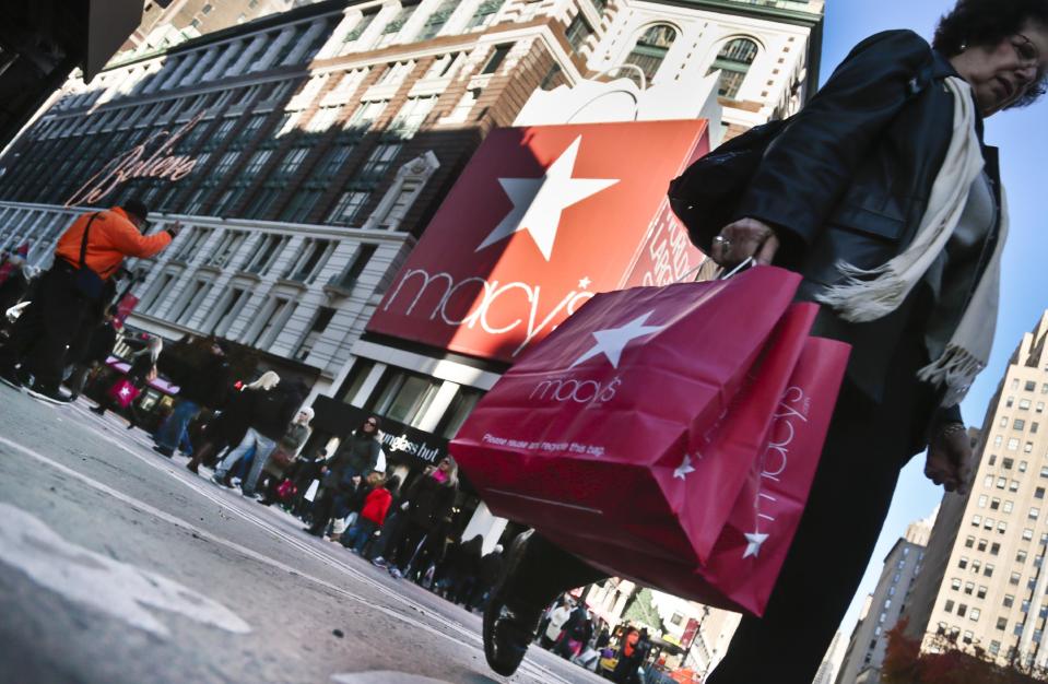 FILE - This Nov. 23, 2013 file photo shows a shopper carries Macy's bags while crossing an intersection outside Macy's in New York. Getting up early on Black Friday for a little shopping? Doing your part on Small Business Saturday and Cyber Monday, too? It’s all in the name of gift-giving _ or at least the guise of it. It seems a lot of consumers are using these sales and retail events to treat themselves to a new little something. (AP Photo/Bebeto Matthews, File)