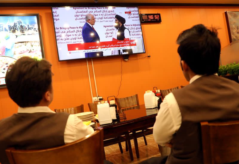 FILE PHOTO: Afghans watch a live TV broadcast at a restaurant during an agreement signing ceremony between the U.S. and the Taliban in Kabul