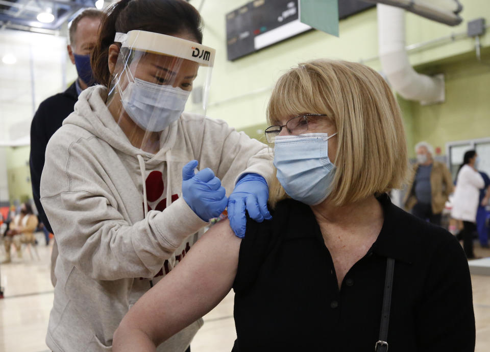 Pacoima Middle School teacher Abigail Abbott, 65, gets her COVID-19 vaccination from Nurse Practitioner Jiyoun Cho, left, as Los Angeles Unified employees received their first dose of the vaccine Wednesday morning. (Al Seib / Los Angeles Times via Getty Images).