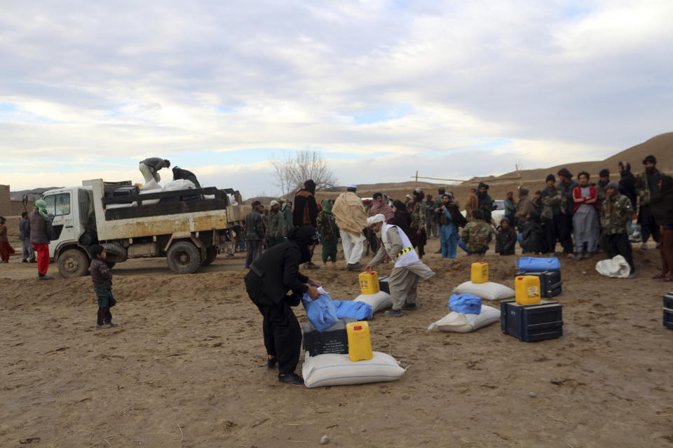 Afghan villagers receive food after their home was damaged by Monday's earthquake in the remote western province of Badghis, Afghanistan, Tuesday, Jan. 18, 2022. The United Nations on Tuesday raised the death toll from Monday's twin earthquakes in western Afghanistan, saying three villages of around 800 houses were flattened by the temblors. (Abdul Raziq Saddiqi)