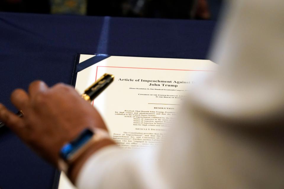 Staff member Latrice Powell placed the article of impeachment against Trump on a table for Pelosi to sign. (Alex Brandon/Associated Press)