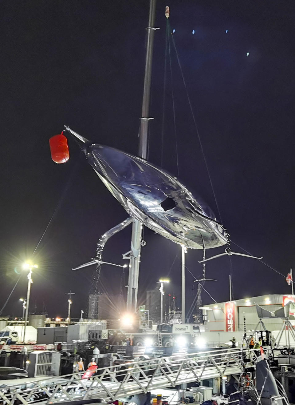 United States' American Magic's damaged boat, Patriot is lifted out of the water at its team base after it capsized during its race against Italy's Luna Rossa on the third day of racing of the America's Cup challenger series on Auckland's Waitemate Harbour, New Zealand, Sunday, Jan. 17, 2021. (Will Trafford/NZ Herald via AP)