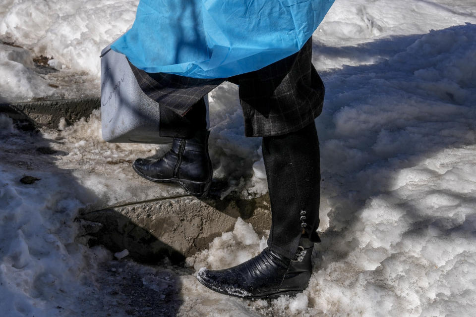 Masrat Farid, a healthcare worker wearing leather boots, stands on snow covered stairs during a COVID-19 vaccination drive in Gagangeer, northeast of Srinagar, Indian controlled Kashmir, Jan. 12, 2022. (AP Photo/Dar Yasin)