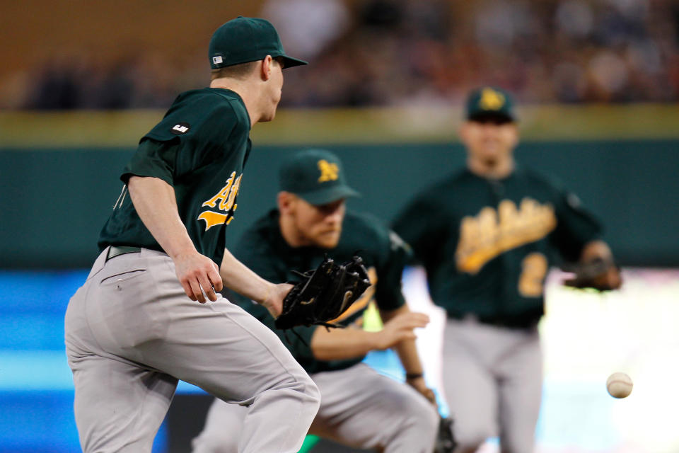 Jarrod Parker #11 (L) of the Oakland Athletics makes an error on a ball hit by Quintin Berry #52 of the Detroit Tigers in the bottom of the third inning which allowed Omar Infante #4 to score during Game One of the American League Division Series at Comerica Park on October 6, 2012 in Detroit, Michigan. (Photo by Gregory Shamus/Getty Images)