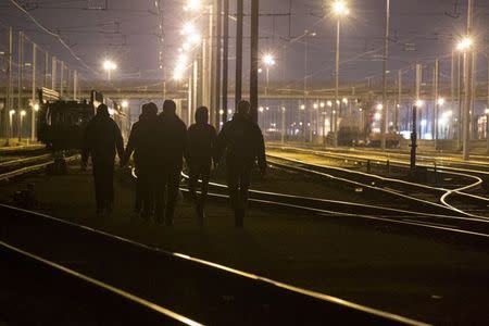 Migrants walk on the railway tracks of the freight shuttle leading to the entrance of the Channel Tunnel in Calais, France, October 14, 2015. REUTERS/Philippe Wojazer