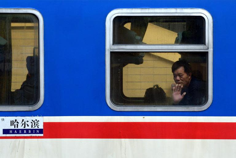 A traveller looks out from a train window at a railway station in Beijing, on January 23, 2014