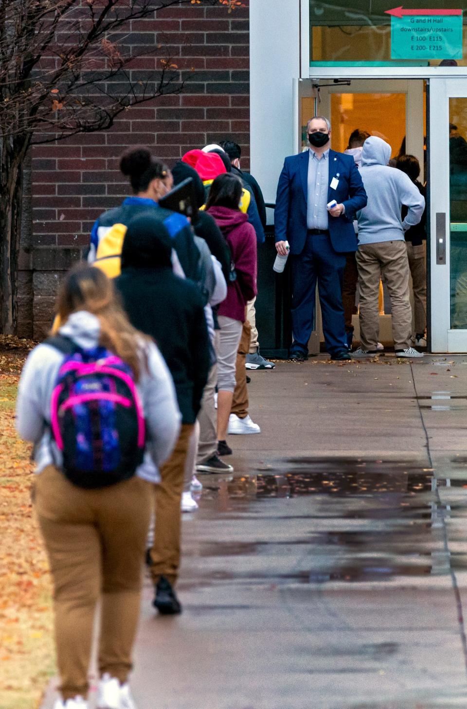 In this Nov. 10, 2020, photo, principal Greg Frederick takes temperatures at the door as students wait in line to enter U.S. Grant High School in Oklahoma City.