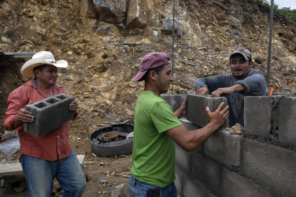 Ivan Varela carries a cinder block as he helps day laborers lay brick for a new home for his parents, who were left homeless in November 2020 when their house was obliterated by a mudslide triggered by Hurricanes Eta and Iota, at the construction site in Mission San Francisco de Asis Honduras, Thursday, July 15, 2021. Each family must send one person to work on the construction of their home. They do not receive wages and if they don’t work, they must pay into a kitty about $6 a day (150 lempiras). (AP Photo/Rodrigo Abd)