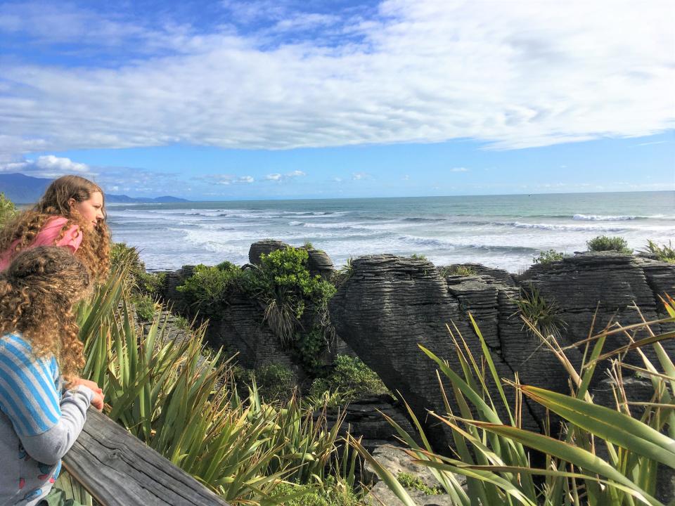 Two girls looking out over a viewpoint of dramatic rocks and the ocean.