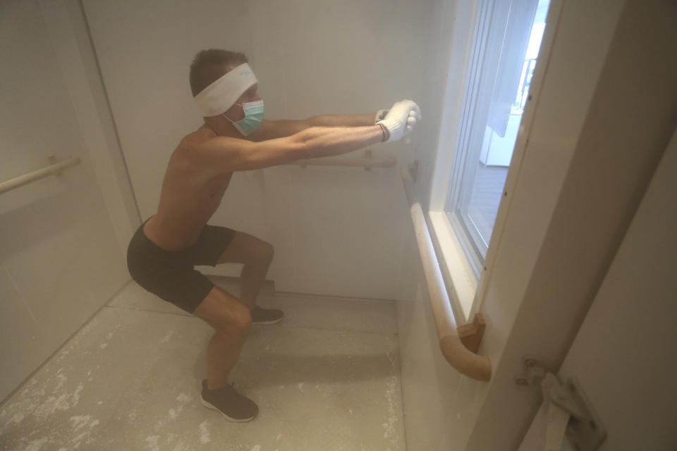 A man exercises during a short workout in a minus 110 degrees Celsius cold cryo chamber in Wertingen, Germany, June 25, 2019. Outside the ice-cold room, Germany faces a heatwave with temperatures near 40 degrees Celsius. (Karl-Josef Hildenbrand/dpa via AP)