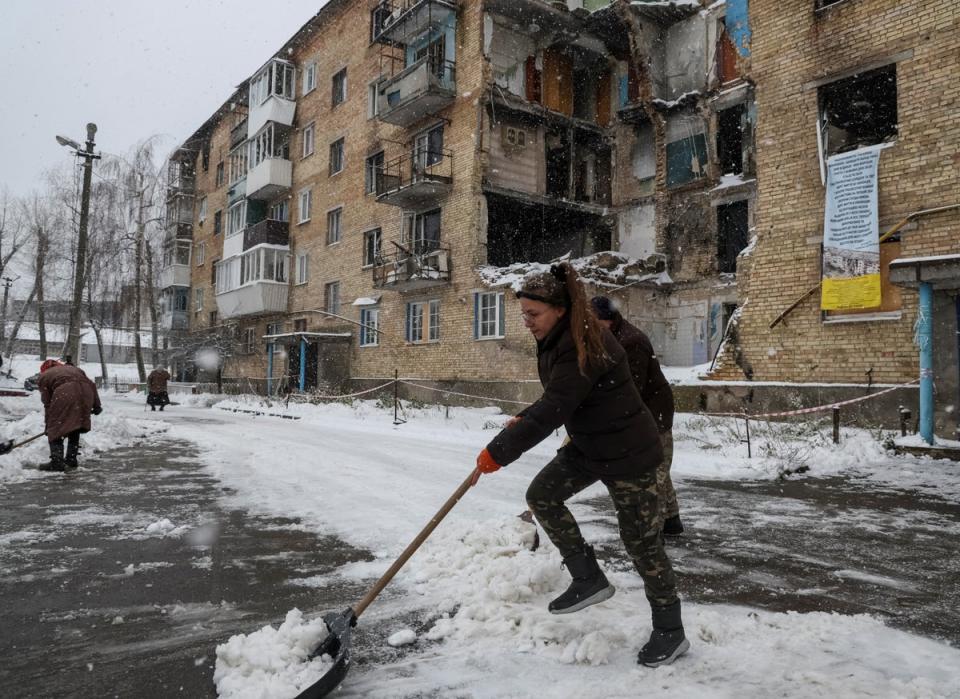 Tetiana Reznychenko, 43, shovels snow near her destroyed building, which has no electricity, heating and water, in the Ukrainian village of Horenka (REUTERS)