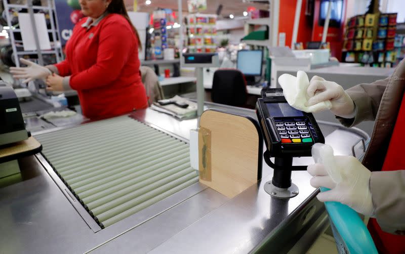 A cashier cleans a payment terminal at a supermarket in Coueron near Nantes, as the spread of the coronavirus disease (COVID-19) continues in France