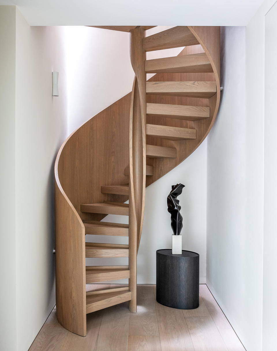 A wooden spiral staircase alongside a statue