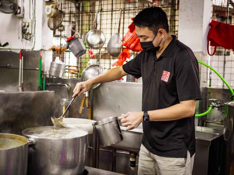 A man making broth in a large pot.