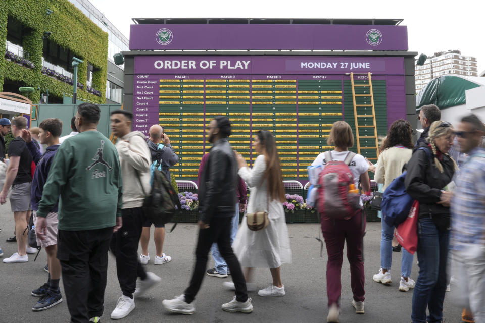 Spectators walk by a board showing the order of play on day one of the Wimbledon tennis championships in London, Monday, June 27, 2022. (AP Photo/Alberto Pezzali)