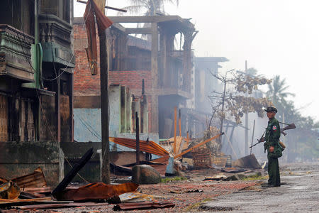 FILE PHOTO: A soldier patrols through a neighbourhood that was burnt during recent violence in Sittwe June 14, 2012. REUTERS/Soe Zeya Tun/File Photo