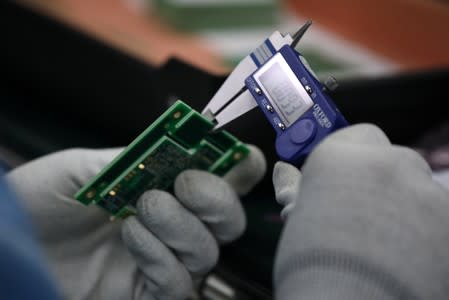 Employee of the automated test equipment designer and solutions provider Aemulus Holdings Berhad inspects a printed circuit board at a production facility in Penang