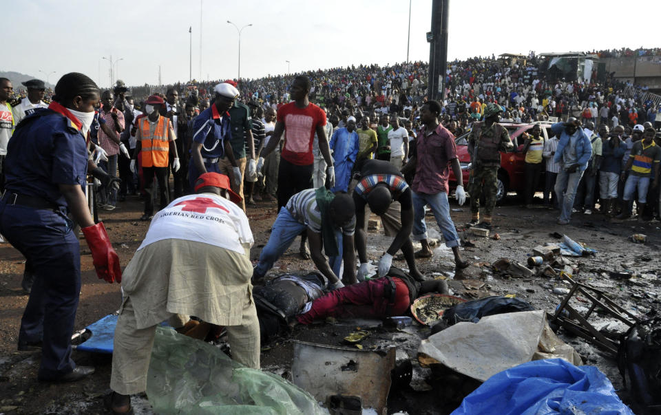 Rescue workers collect the bodies of victims as people gather at the site of a blast at the Nyanya Motor Park, about 16 kilometers (10 miles) from the center of Abuja, Nigeria, Monday, April 14, 2014. An explosion blasted through a busy commuter bus station on the outskirts of Abuja before 7 a.m. (0600 GMT) Monday as hundreds of people were traveling to work. (AP Photo/Gbemiga Olamikan)