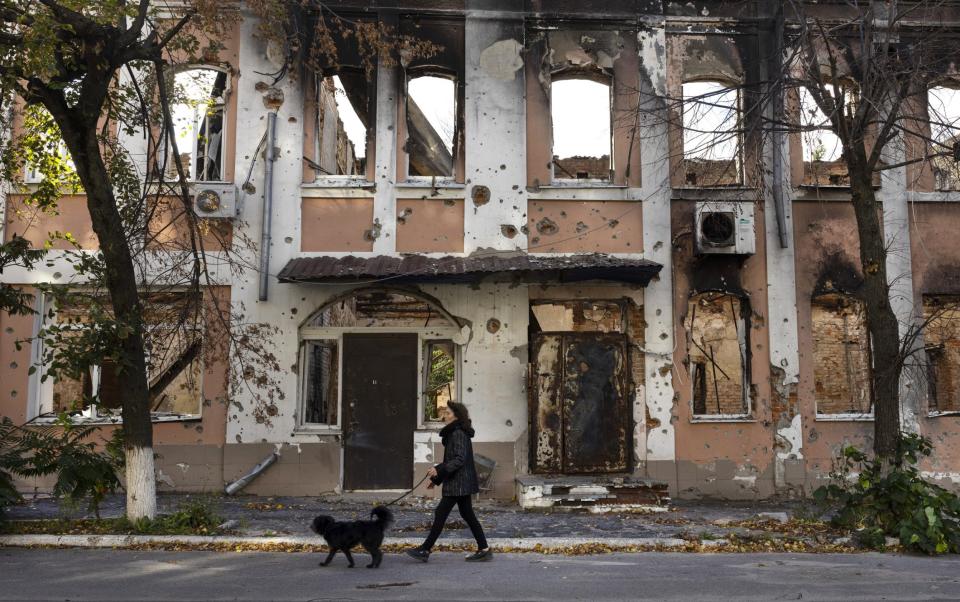 A woman walks her dog outside a destroyed building in Izium, Ukraine - Paula Bronstein/Getty Images