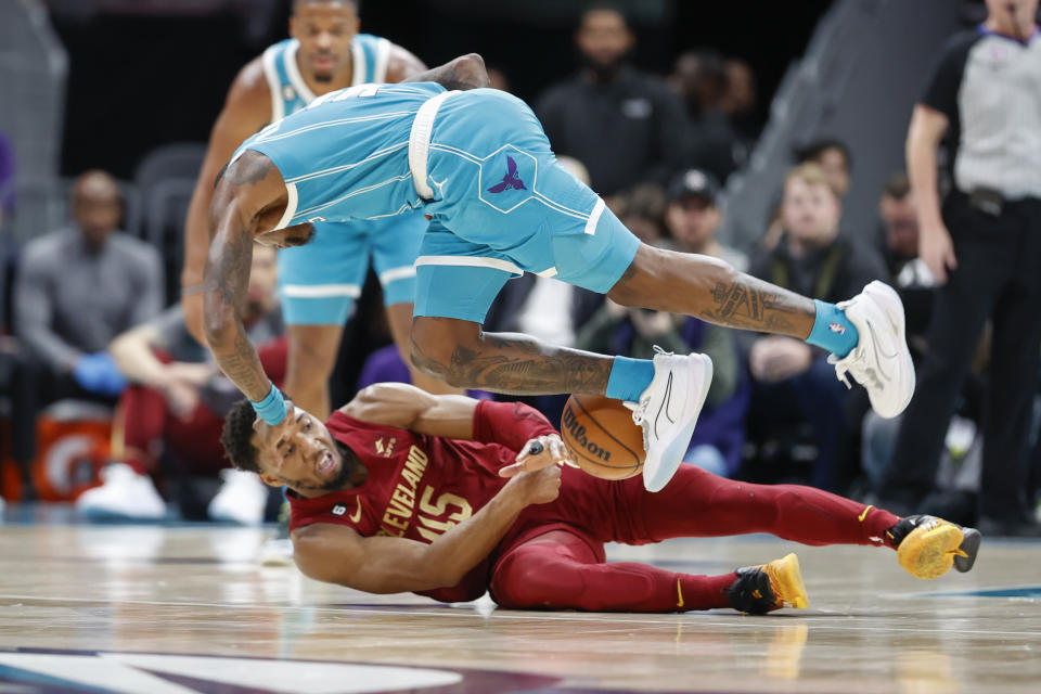 Cleveland Cavaliers guard Donovan Mitchell (45) and Charlotte Hornets guard Terry Rozier fight for a loose ball during the first half of an NBA basketball game in Charlotte, N.C., Sunday, March 12, 2023. (AP Photo/Nell Redmond)