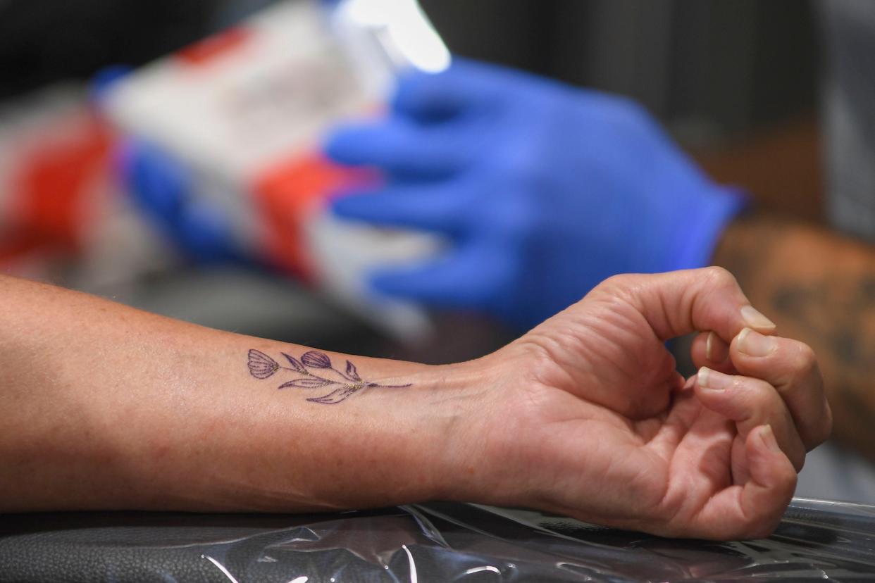 Tara Thomas waits anxiously as Jonah Huff prepares the tattoo setup during the Tattoo Garden's 