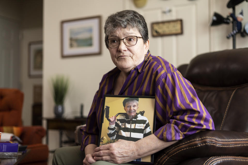 Georgene White sits for a portrait with a photo of her mother, Teri Sheridan, in Belvidere, N.J., Thursday, April 20, 2023. At age 93, struggling with the effects of a stroke, heart failure and recurrent cancer, Sheridan was ready to end her life using New Jersey's law that allows medically assisted suicide - but she was bedbound, too sick to travel. So on Nov. 17, 2022, surrounded by three of her children, Sheridan drank a lethal dose of drugs prescribed by a doctor she had never met in person, only online. She died within minutes. (AP Photo/Matt Rourke)