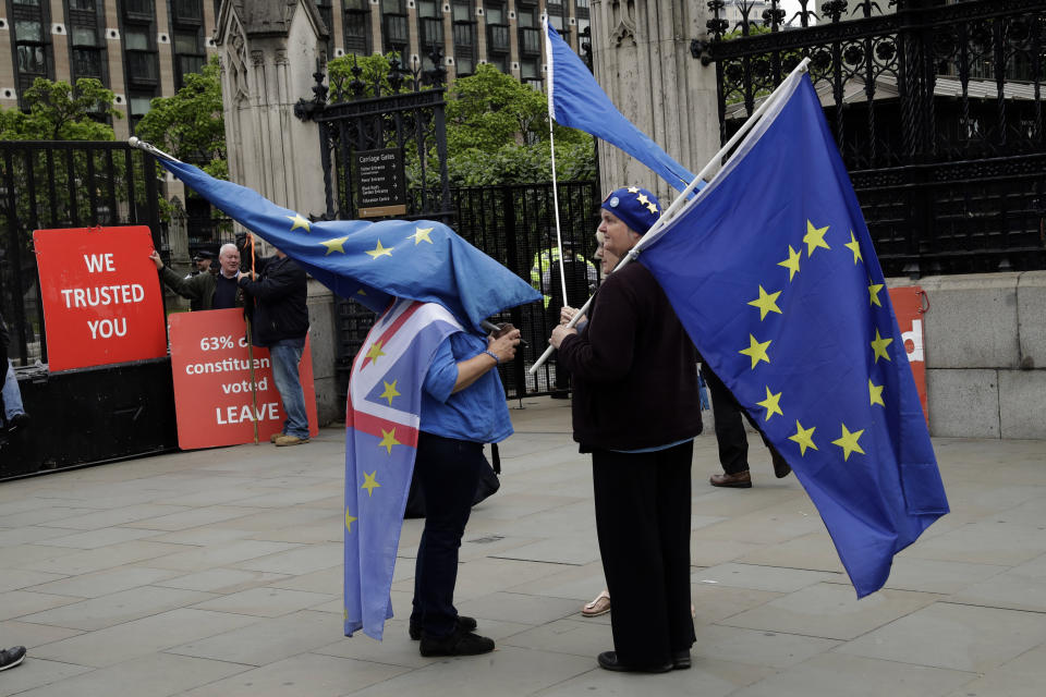 Anti-Brexit remain supporters stand with European flags and pro-Brexit leave supporters hold red placards as they all protest outside the Houses of Parliament in London, Wednesday, June 19, 2019. Britain's Conservative Party are set to kick one more candidate out of the contest to become the country's next prime minister, as rivals scramble to catch front-runner Boris Johnson. The five-strong field will be narrowed in elimination votes by Tory lawmakers Wednesday and Thursday, with the two top candidates going to a runoff of party members across the country. (AP Photo/Matt Dunham)