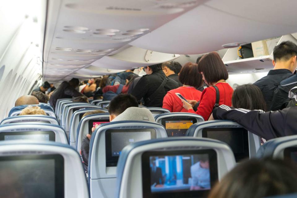 <p>Getty</p> Stock image of passengers standing in the aisle as they wait to leave the plane. 