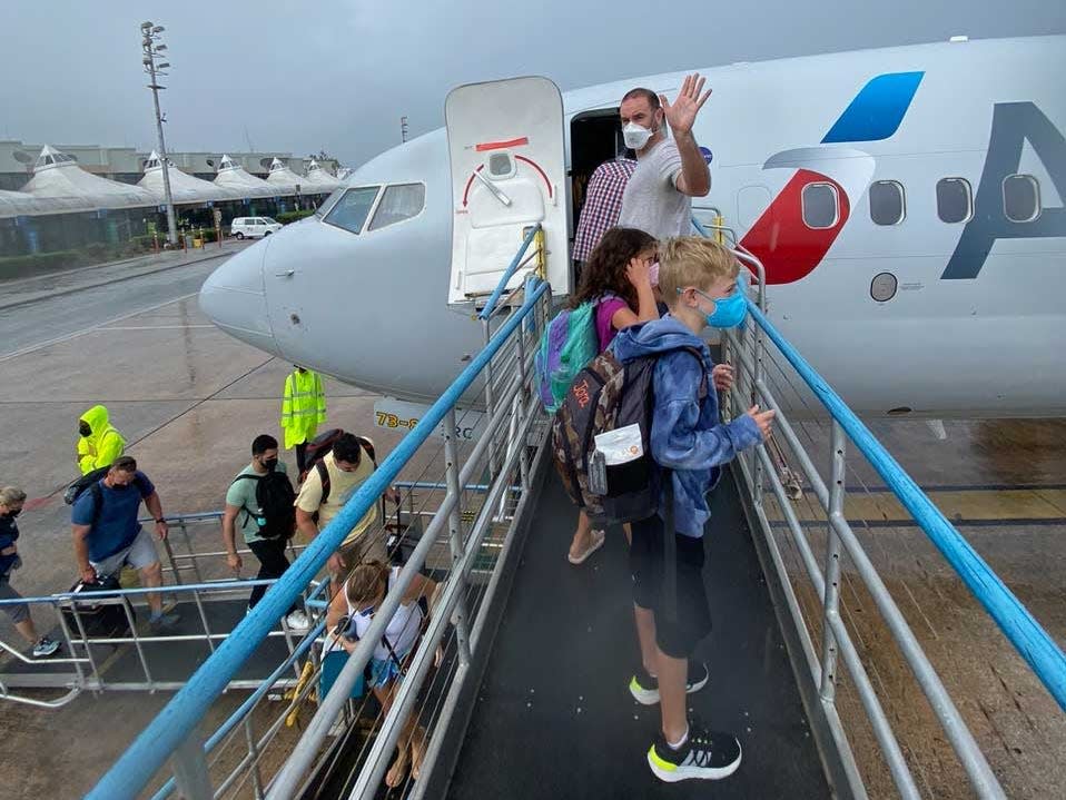 A man waving as he board an American Airlines plane with his two children.