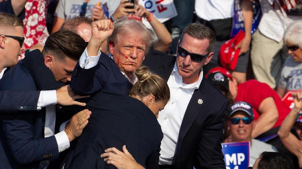 PHOTO: Republican candidate Donald Trump is seen with blood on his face surrounded by secret service agents as he is taken off the stage at a campaign event at Butler Farm Show Inc. in Butler, Pa., July 13, 2024.  (Rebecca Droke/AFP via Getty Images)