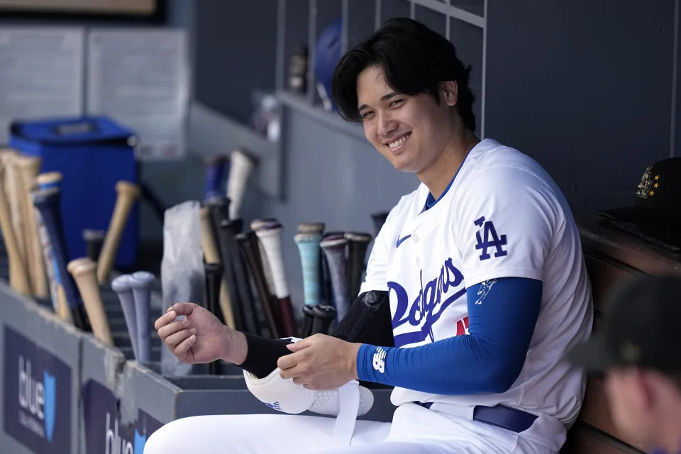 Los Angeles Dodgers designated hitter Shohei Ohtani smiles as he sits in the dugout prior to a baseball game against the Cincinnati Reds Sunday, May 19, 2024, in Los Angeles. (AP Photo/Mark J. Terrill)