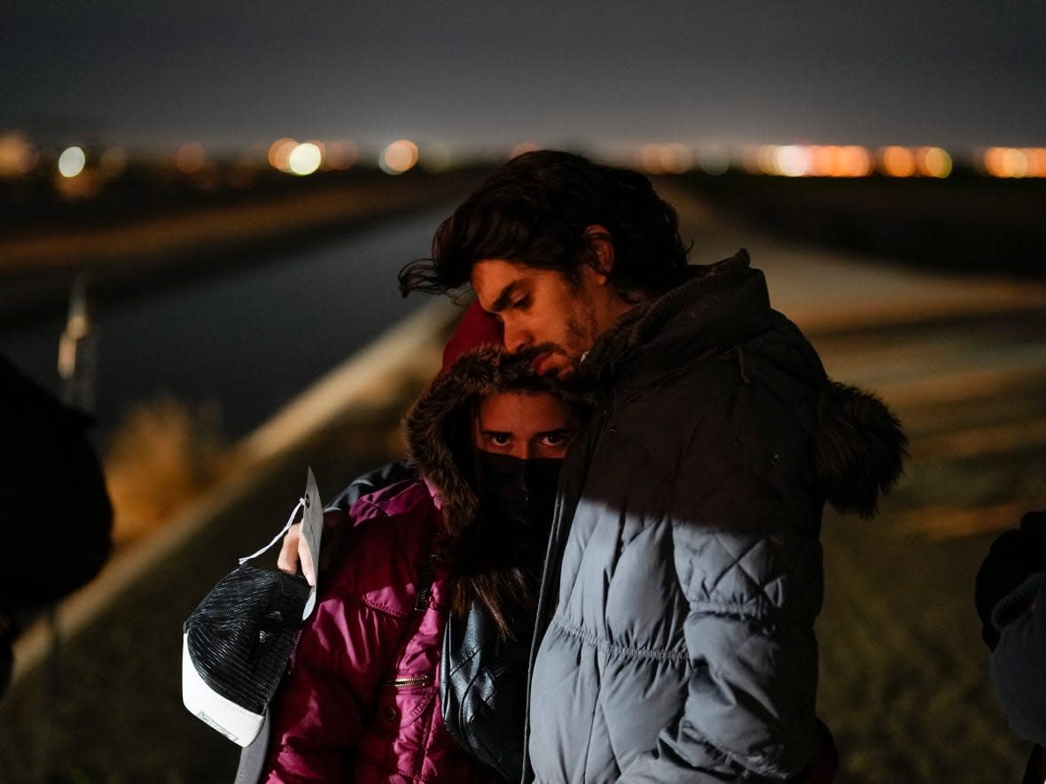 Cuban migrant Mario Perez holds his wife as they wait to be processed to seek asylum after crossing the border into the United States on Jan. 6, 2023, near Yuma, Ariz. (Gregory Bull/Associated Press - image credit)