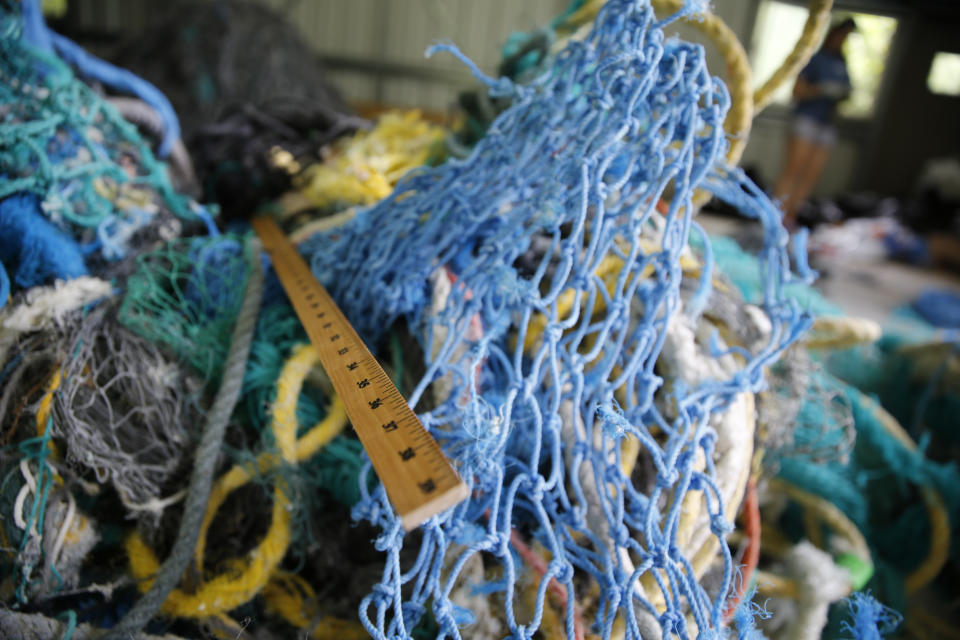 A measuring stick lays among ghost nets at Hawaii Pacific University's Center for Marine Debris Research on Wednesday, May 12, 2021 in Kaneohe, Hawaii. Researchers are conducting a study that will attempt to trace derelict fishing gear that washes ashore in Hawaii back to the manufacturers and fisheries that it came from. (AP Photo/Caleb Jones)