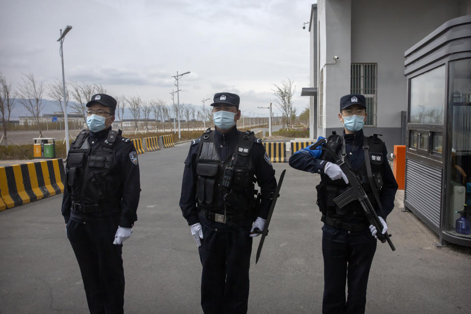 FILE - Police officers stand at the outer entrance of the Urumqi No. 3 Detention Center in Dabancheng in western China's Xinjiang Uyghur Autonomous Region on April 23, 2021. State officials took AP journalists on a tour of a "training center" turned detention site in Dabancheng sprawling over 220 acres and estimated to hold at least 10,000 prisoners - making it by far the largest detention center in China and among the largest on the planet. (AP Photo/Mark Schiefelbein, File)