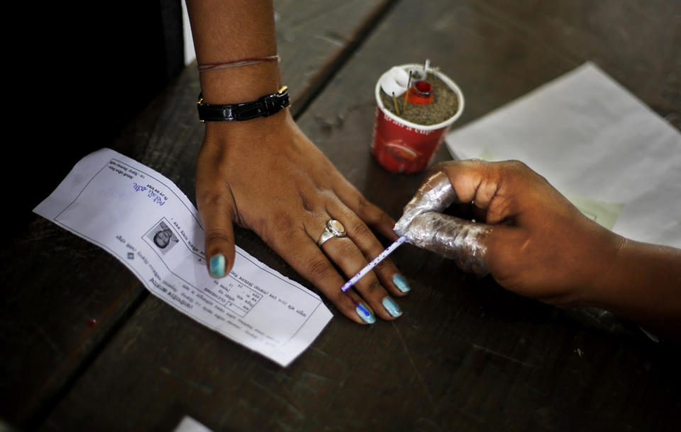 An Indian election officer applies an indelible ink mark on the finger of a woman during the first phase of elections in Dibrugarh, in the northeastern state of Assam, India, Monday, April 7, 2014. (AP Photo/Altaf Qadri)