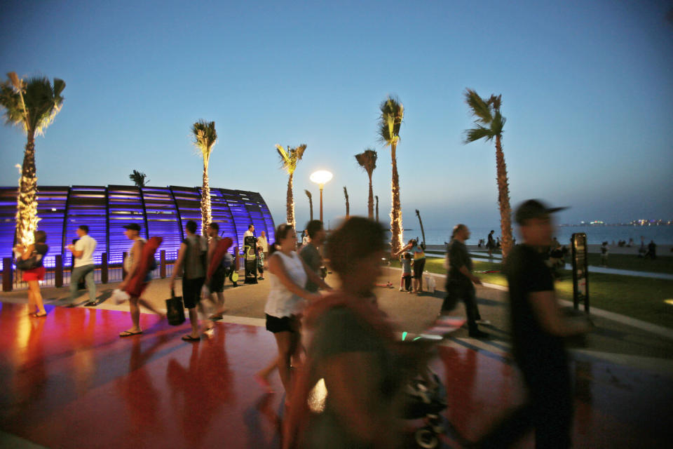 In this Monday, April 21, 2014 photo, people walk past a gym at the beach in Dubai, United Arab Emirates. The beach _ which overlooks the city’s iconic Palm Jumeirah island, far right, is now more popular than ever after the recent opening of a sleek new shopping and entertainment promenade. (AP Photo/Kamran Jebreili)
