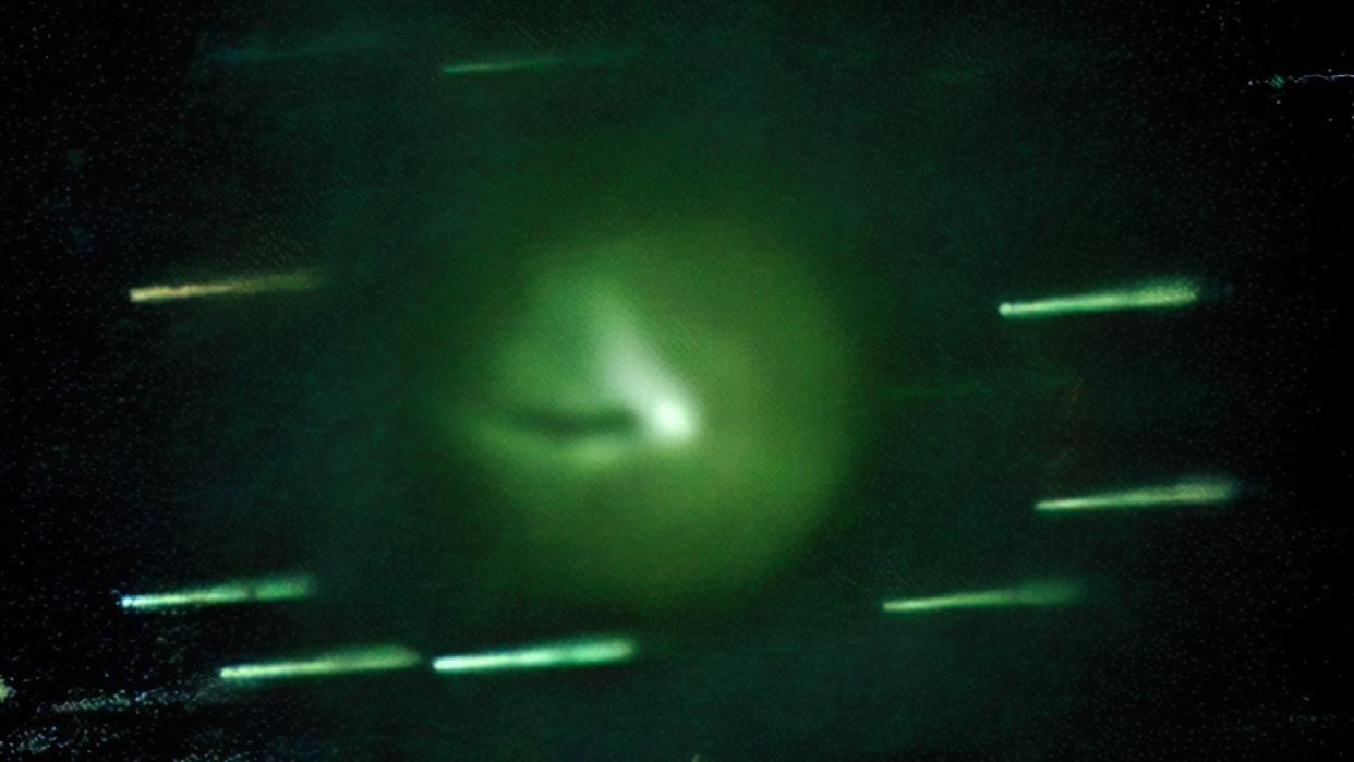 A close up of a green comet with a shadow in its coma