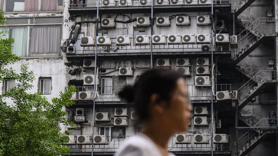 2024 年 4 月 30 日，一名女子走过首尔一栋建筑外的空调机组。 - Anthony Wallace/法新社/盖蒂图片社