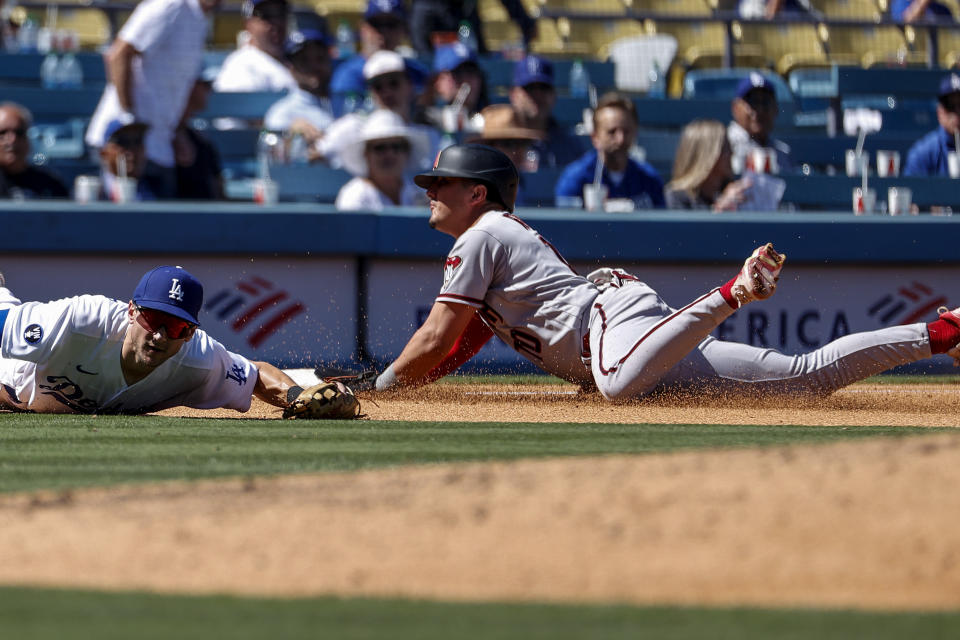 Arizona Diamondbacks' Josh Rojas, right, dives safely into third as Los Angeles Dodgers' Trea Turner waits for the throw during the fifth inning of a baseball game Tuesday, Sept 20, 2022, in Los Angeles. (AP Photo/Ringo H.W. Chiu)
