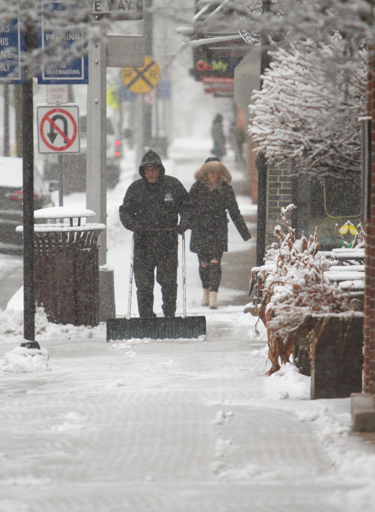 David Ulrich clears snow from the sidewalk in front of the Brighton Coffeehouse and Theater as a winter storm starts Wednesday, Feb. 2, 2022. Ulrich, who is a friend of the downtown Brighton business owner, regularly volunteers with such tasks.