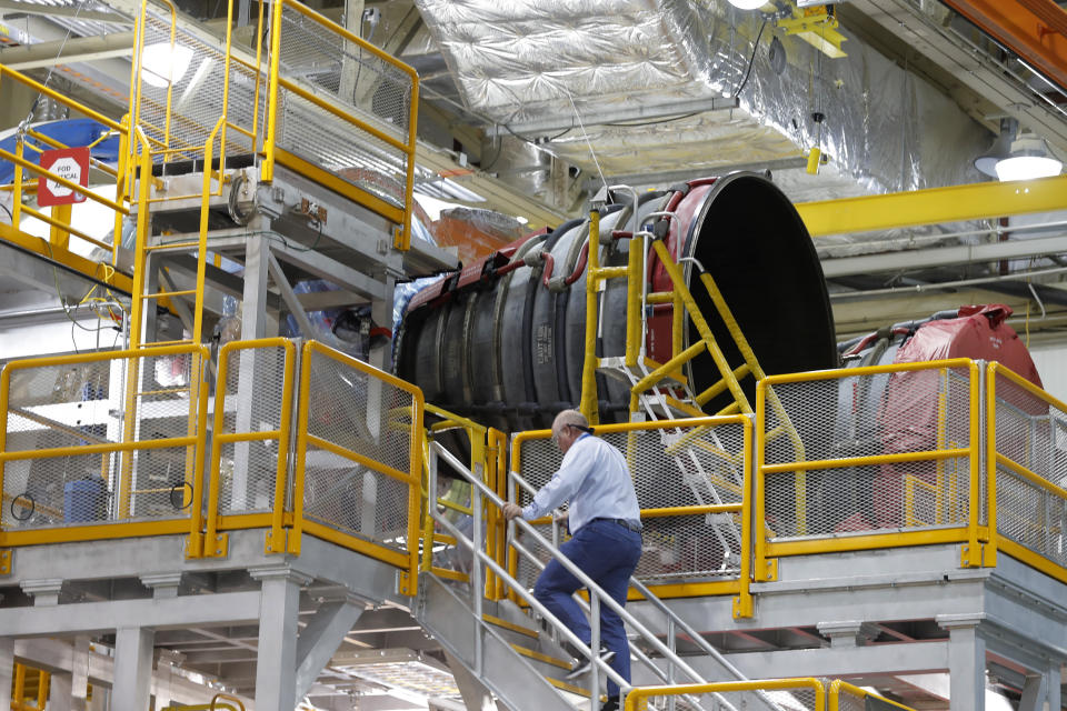 An employee walks up to two of the four rocket engines of NASA's Space Launch System (SLS) as the Artemis 1 rocket core stage is assembled at the NASA Michoud Assembly Center in New Orleans, Monday, Dec. 9, 2019. (AP Photo/Gerald Herbert)