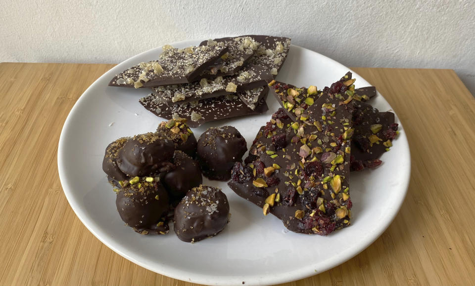 This image shows a plate of chocolate truffles and chocolate bark. Rather than spending on store-bought chocolates for Valentine’s Day, make them together as a fun way to spend the evening with your Valentine. (Albert Stumm via AP)