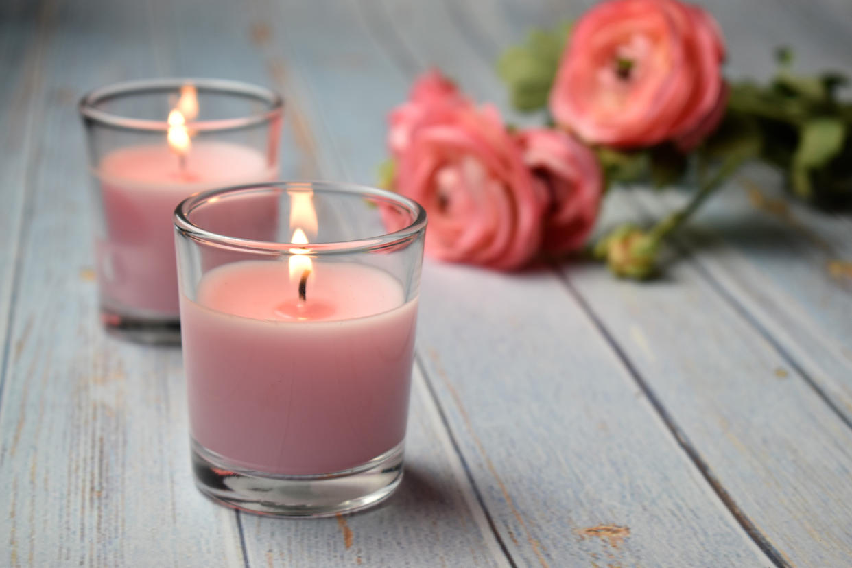 Scented pink candles with flowers in the background, close-up