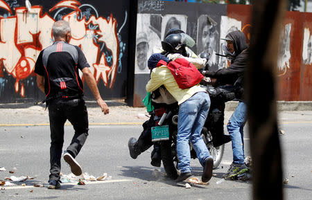 Demonstrators grab a riot police officer at a rally against Venezuela's President Nicolas Maduro's government in Caracas, Venezuela April 10, 2017. REUTERS/Christian Veron