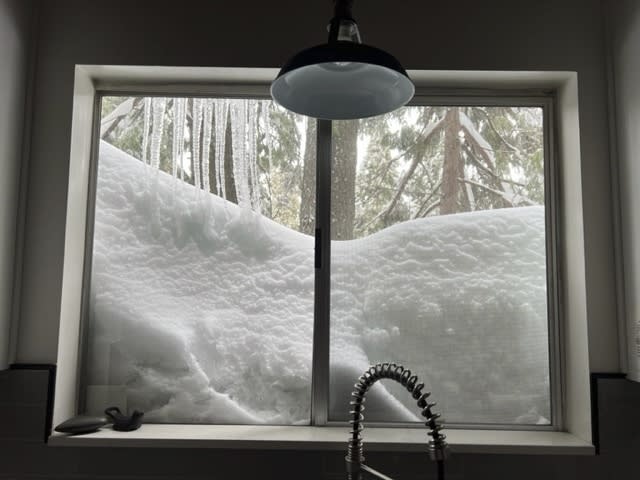 Snow is piled up against the kitchen window of Jennifer Cobb's house in Lake Arrowhead on Tuesday, Feb. 28, 2023 in the San Bernardino Mountains of San Bernardino County, Calif. Beleaguered Californians got hit again Tuesday as a new winter storm moved into the already drenched and snow-plastered state, with blizzard warnings blanketing the Sierra Nevada and forecasters warning residents that any travel was dangerous. (Jennifer Cobb via AP)
