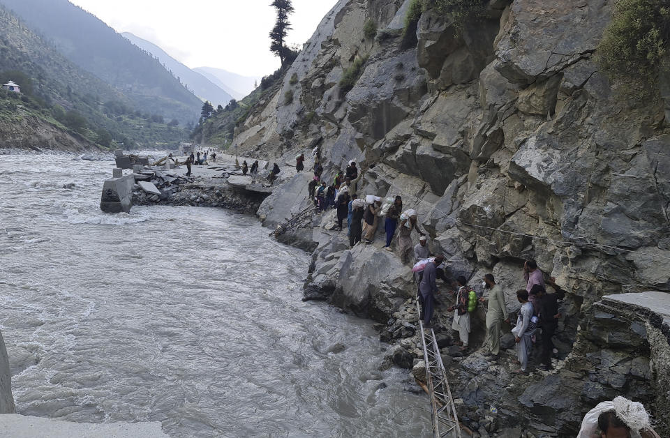 Local residents cross a portion of road destroyed by floodwaters in Kalam Valley