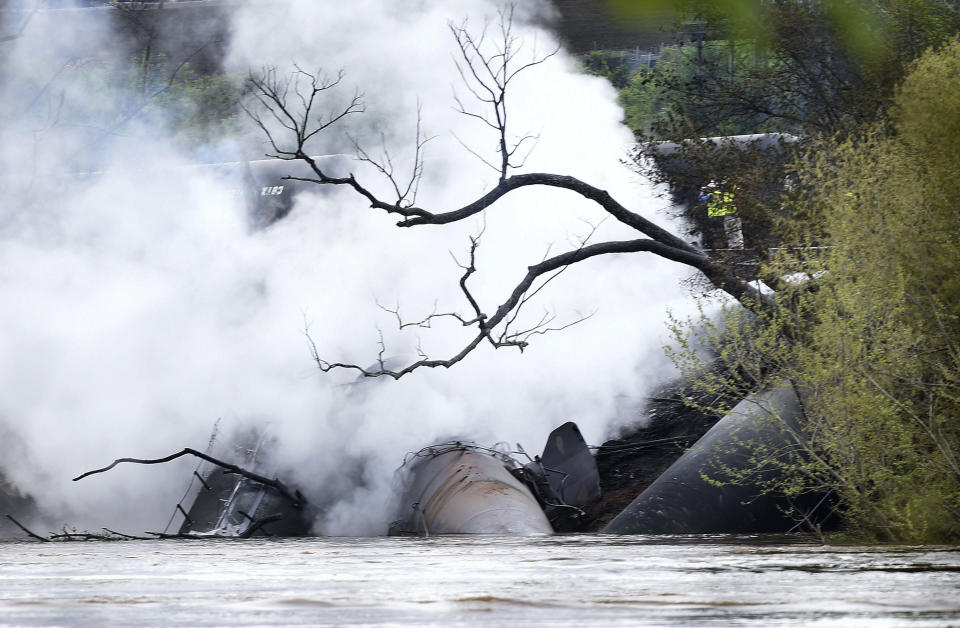 Firefighters and rescue personnel work along the tracks where several CSX tanker cars carrying crude oil derailed and caught fire along the James River in Lynchburg, Va., Wednesday, April 30, 2014. Nearby buildings were evacuated for a time, but officials said there were no injuries and the city on its website and Twitter said firefighters on the scene made the decision to let the fire burn out. (AP Photo/News & Daily Advance, Autumn Parry)